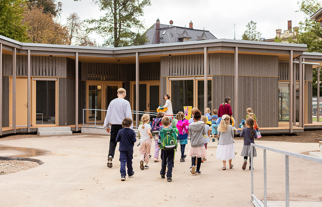 Kinder laufen über den Schulhof in ein Gebäude der Schöpflin Schule.